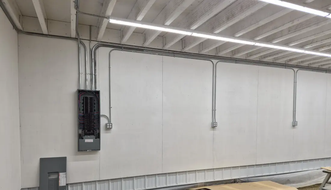 Electrical panel and conduit runs installed in a shop